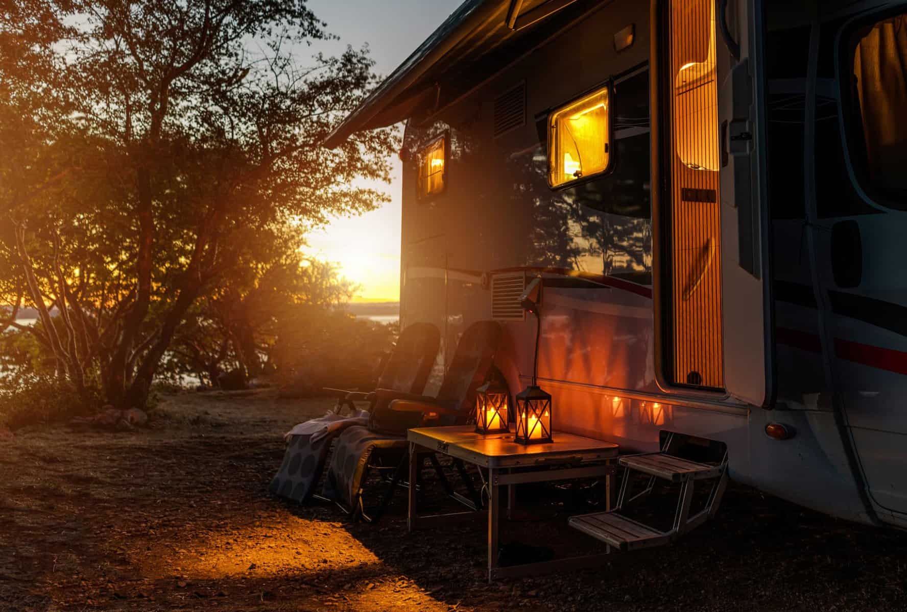 An RV parked on the side of a lake at sunset, representing the Campground Association.