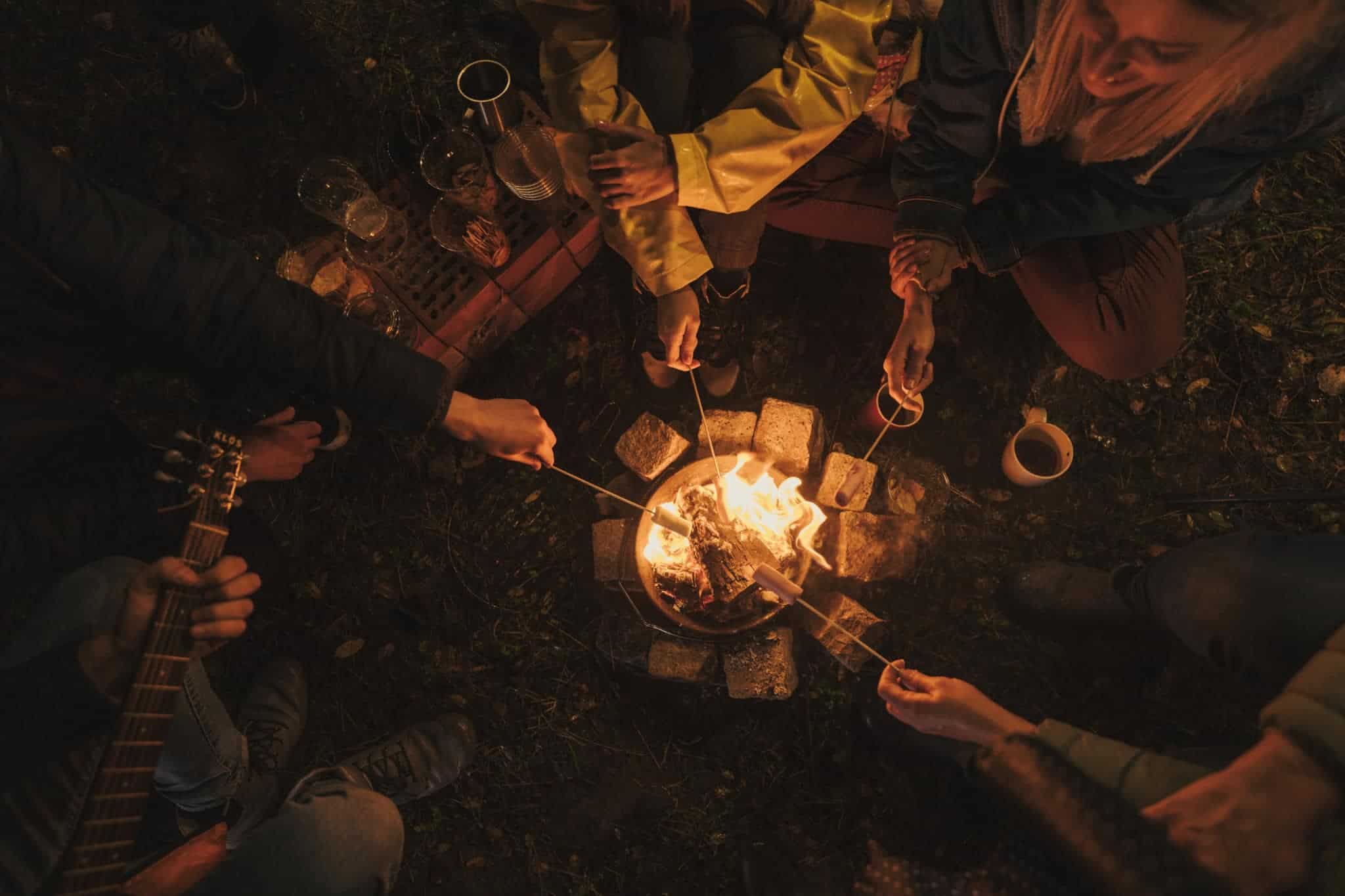 A group of people enjoying an MC Fireside Chat outdoors, as they sit around a campfire.