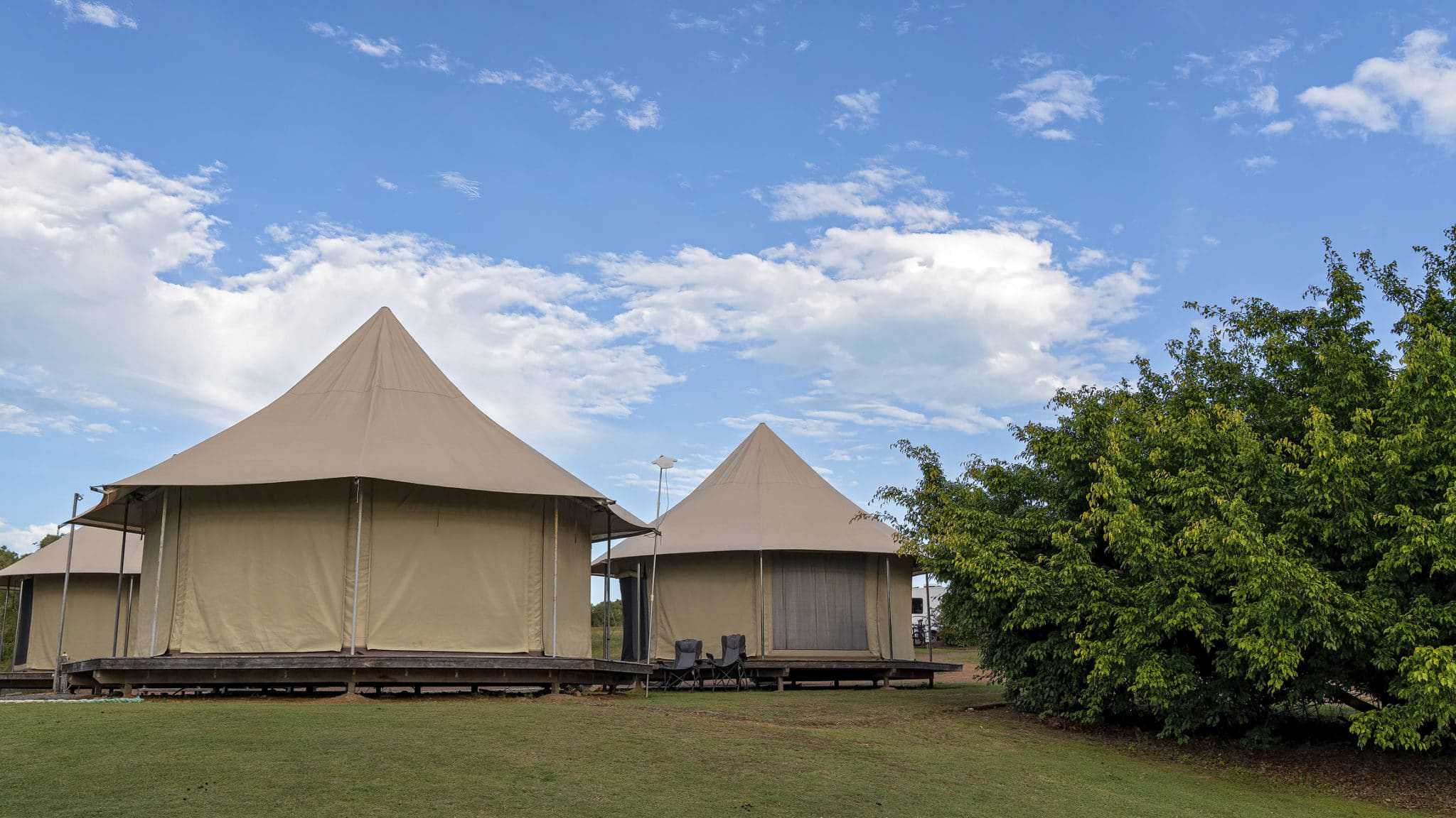 Two camping tents sitting on a grassy field at an Eco Resort in Australia.