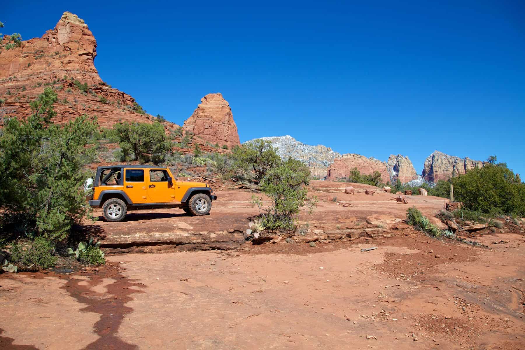 A 4WD-accessible orange jeep is parked on a rocky trail in Sedona.