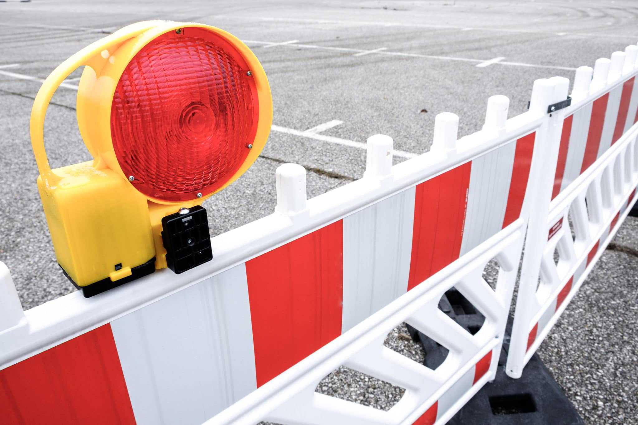 A traffic light on a barrier in an Access Road parking lot.