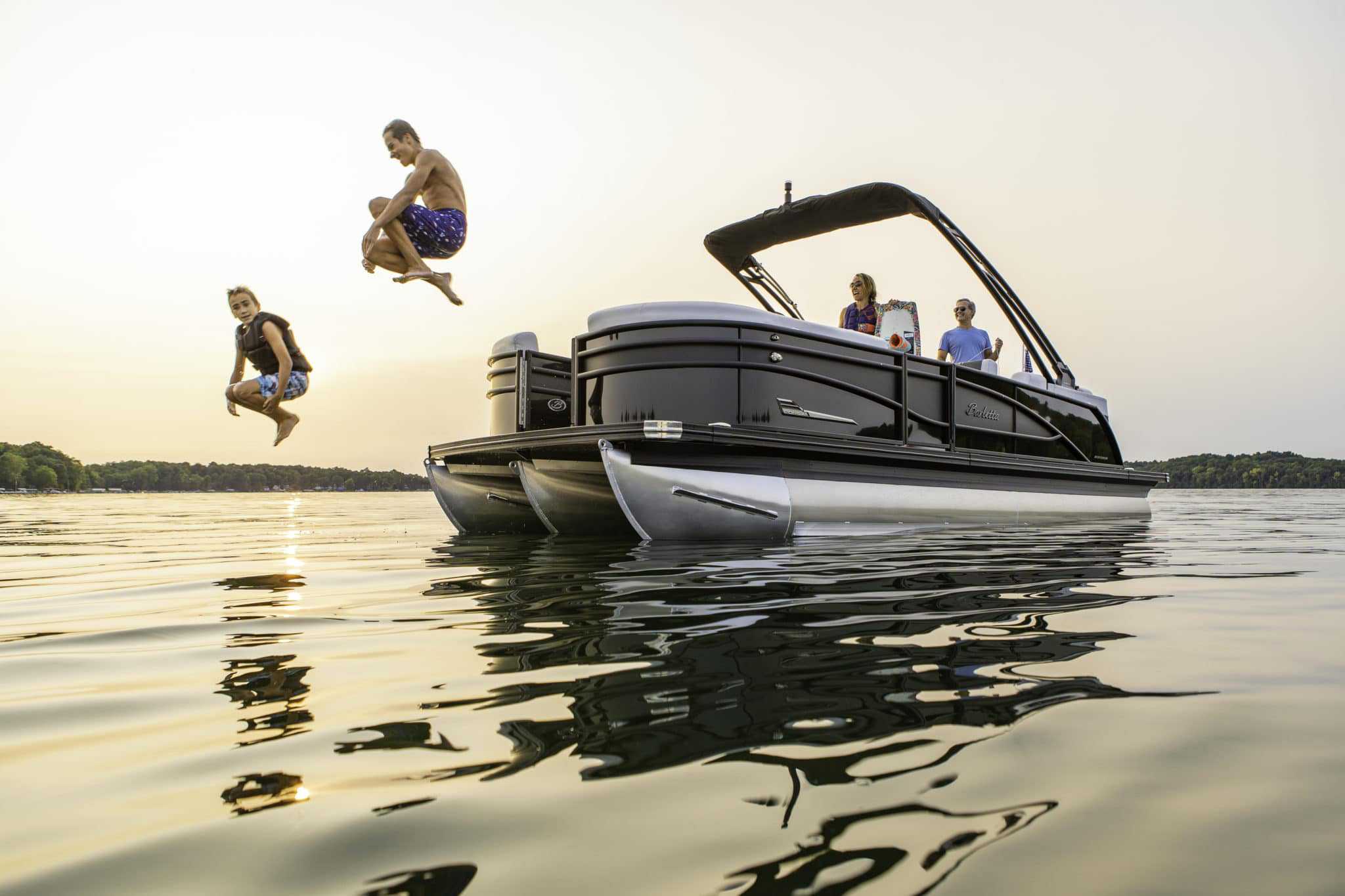 A group of people jumping off of a pontoon boat manufactured by Barletta Pontoon Boats.