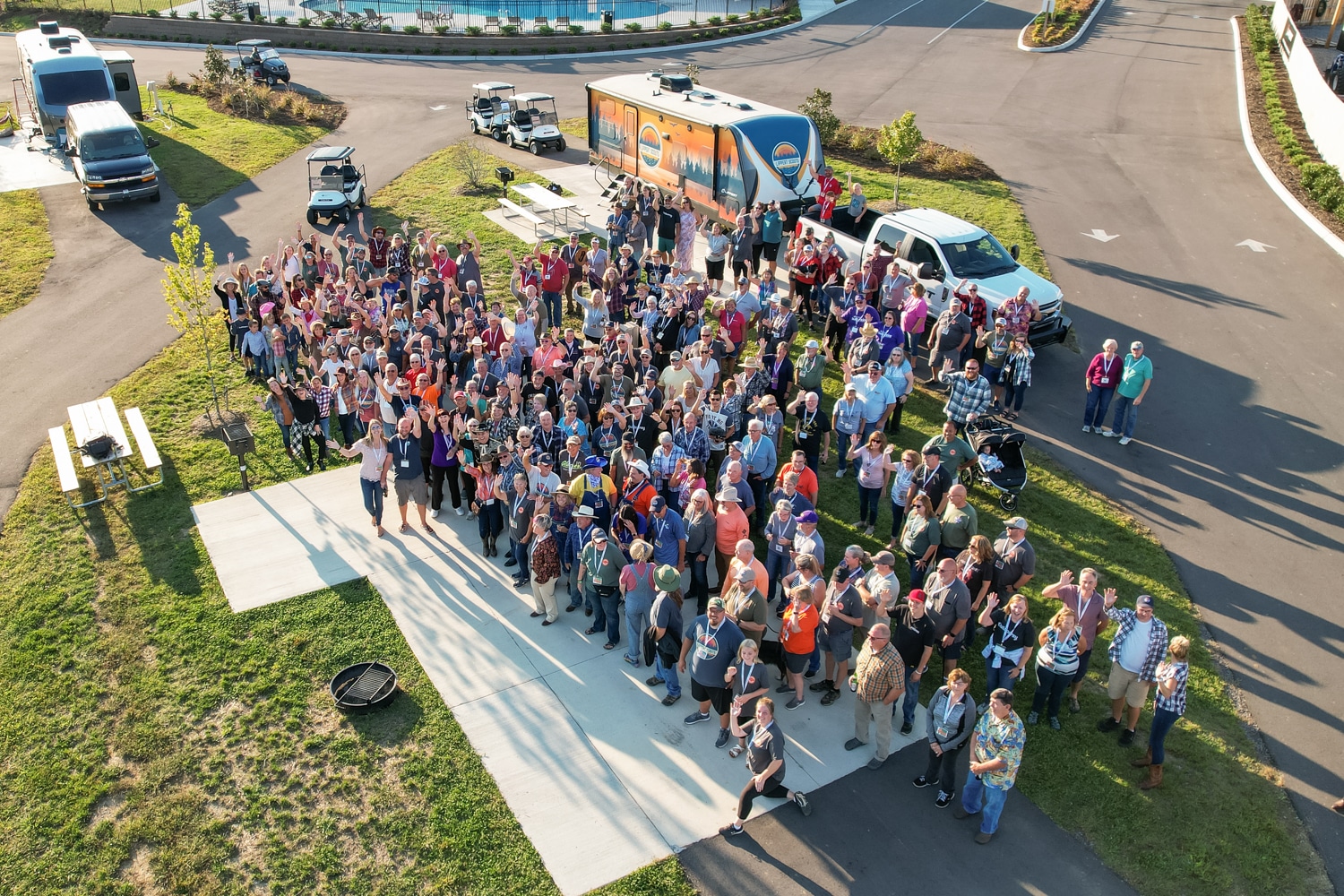 An aerial view of a group of people standing in front of a Lippert truck at a Rally.
