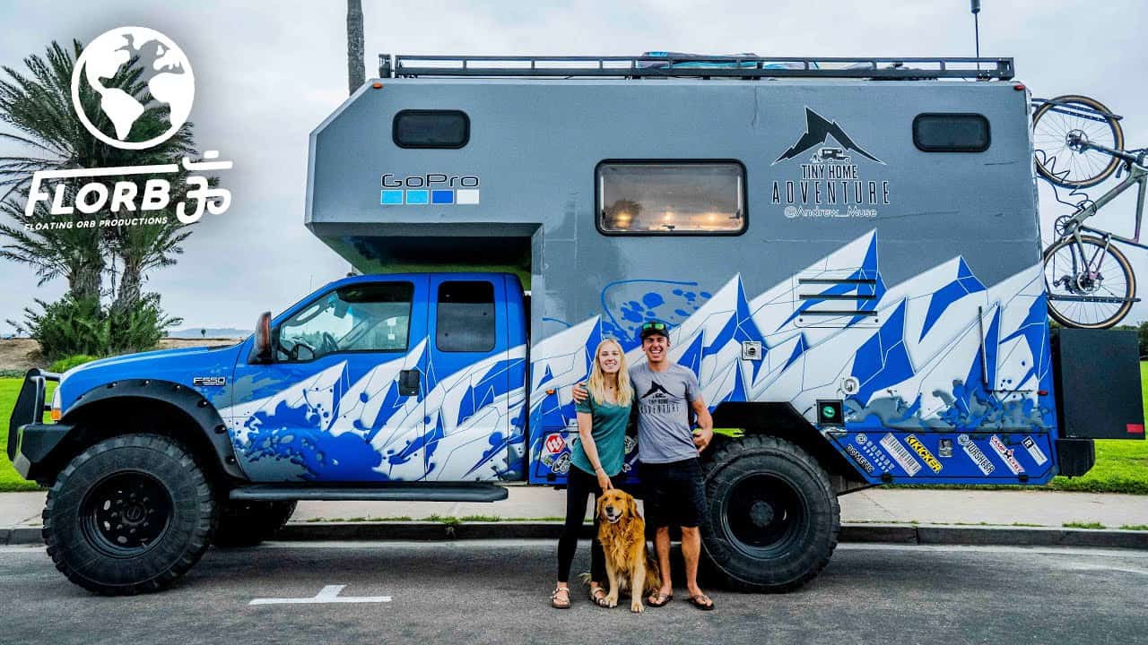 A couple and their dog stand next to a blue and white Truck Conversion.