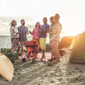 A group of friends standing near a tent on the beach.