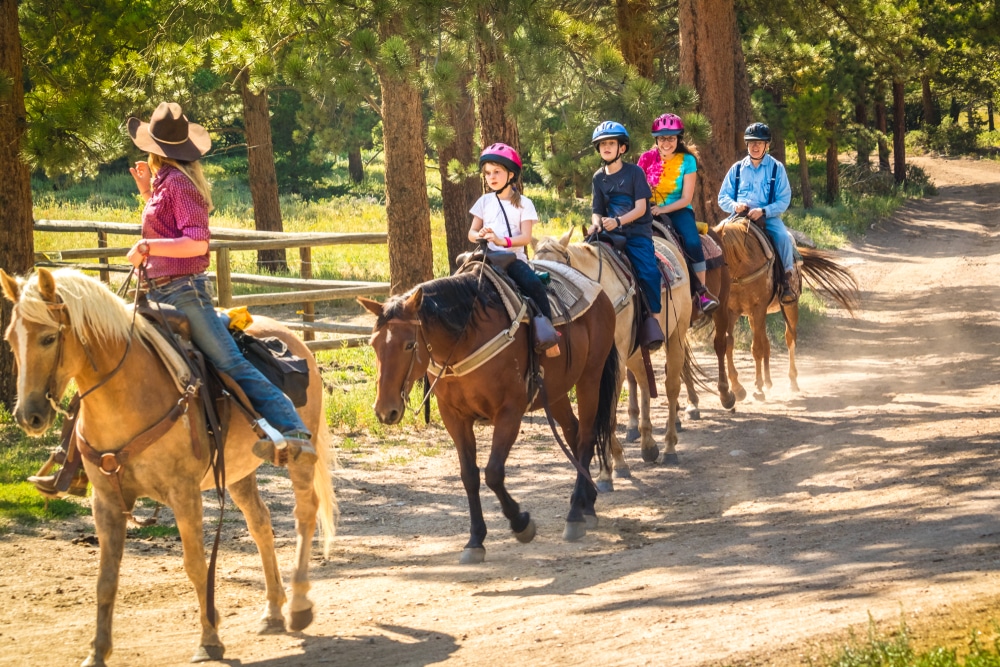 A group of people riding horses on a dirt road.