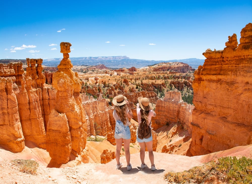 Two women standing at the top of a cliff in bryce canyon national park.
