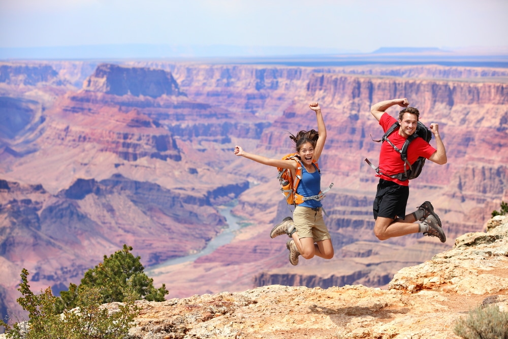 Two people admiring the grandeur of the Grand Canyon while standing on a cliff.