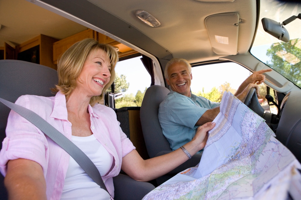 A man and woman in a Heartland RV, carefully studying new floorplans for their luxurious fifth wheel.