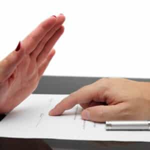 A person signing a document with their hand.
