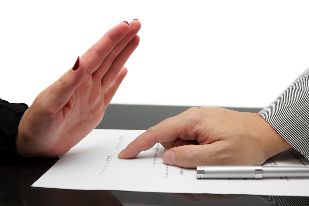 A person signing a document with their hand.