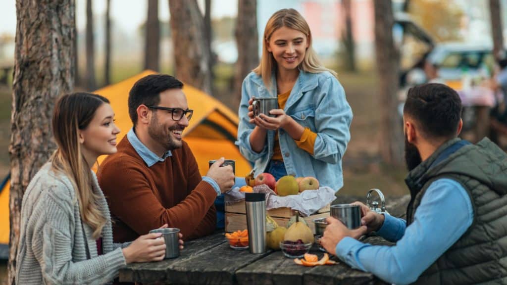 A group of friends sitting around a picnic table in the campground.
