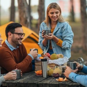 A group of friends sitting around a picnic table in the campground.