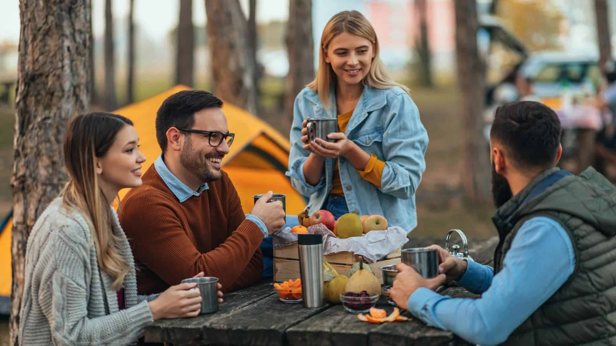 A group of friends sitting around a picnic table in the campground.