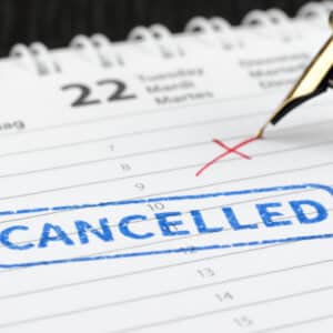 A pen is writing the word cancelled on a calendar.