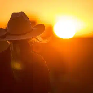 A woman wearing a cowboy hat at sunset.