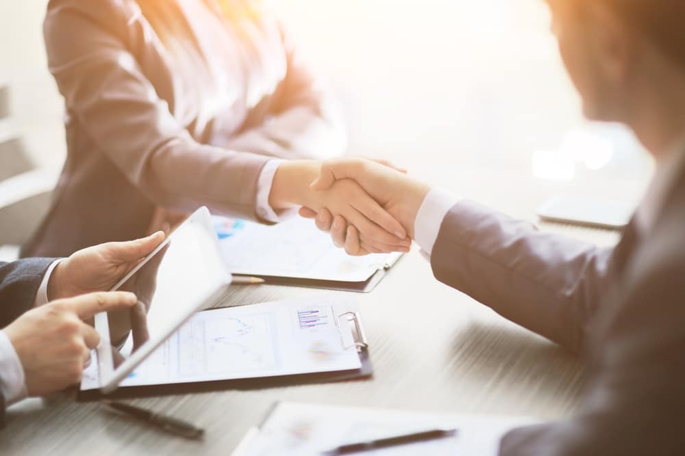 Two business people from THOR Industries and L Catterton shaking hands at a meeting.