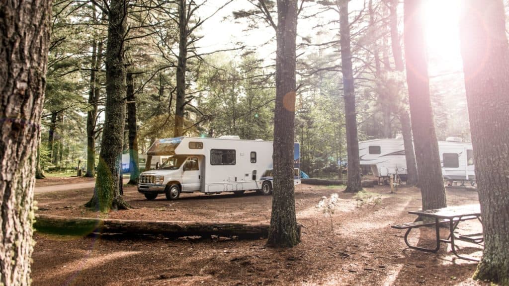 A serene campground for sale, nestled in a wooded area with a picturesque group of RVs.