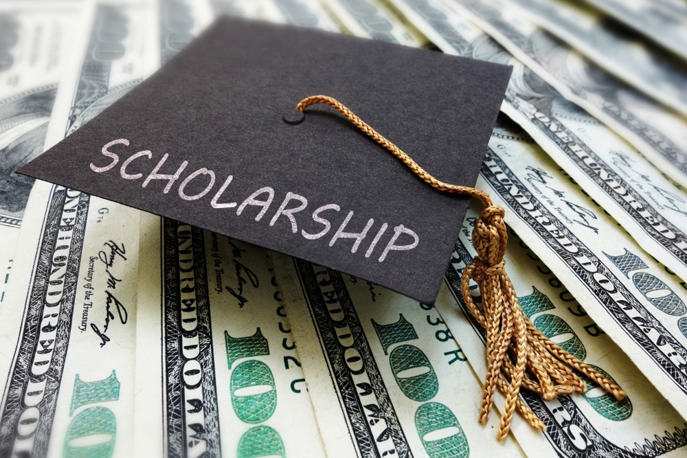 A graduation cap with the word scholarship on top of a pile of money, awarded to a recipient of the Mike Molino RV Learning Center College Scholarship.