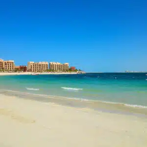A glamp on Dubai beach with people and buildings in the background.