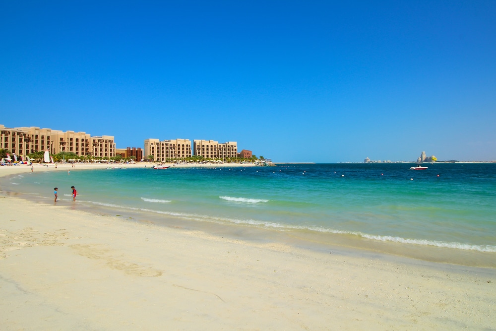 A glamp on Dubai beach with people and buildings in the background.