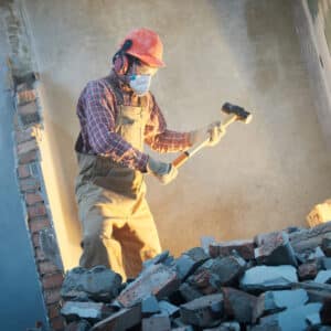 A construction worker is hammering a wall with a hammer.