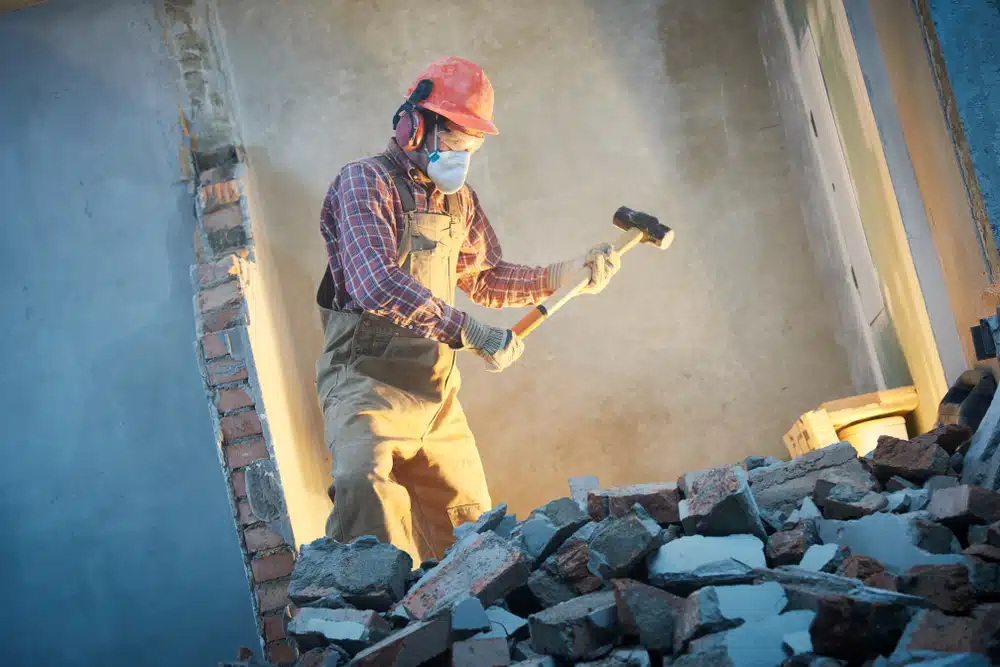 A construction worker is hammering a wall with a hammer.