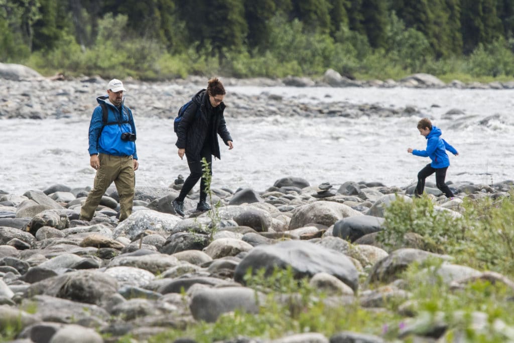 A virtual public meeting discussing trail development near a river, showcasing a group of people walking on rocks.