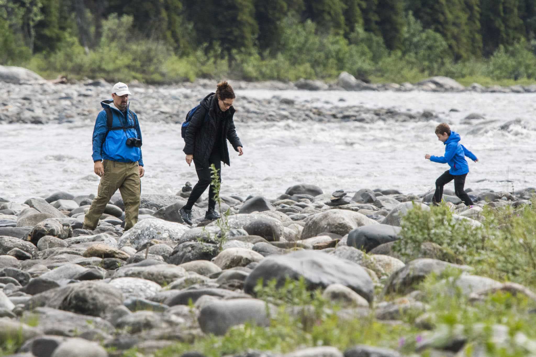 A virtual public meeting discussing trail development near a river, showcasing a group of people walking on rocks.