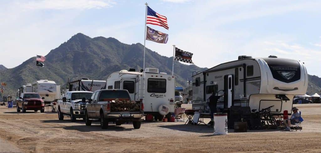 A group of RVs parked in a parking lot, including RVnGO, the Official RV Rental Partner for Phoenix Raceway.