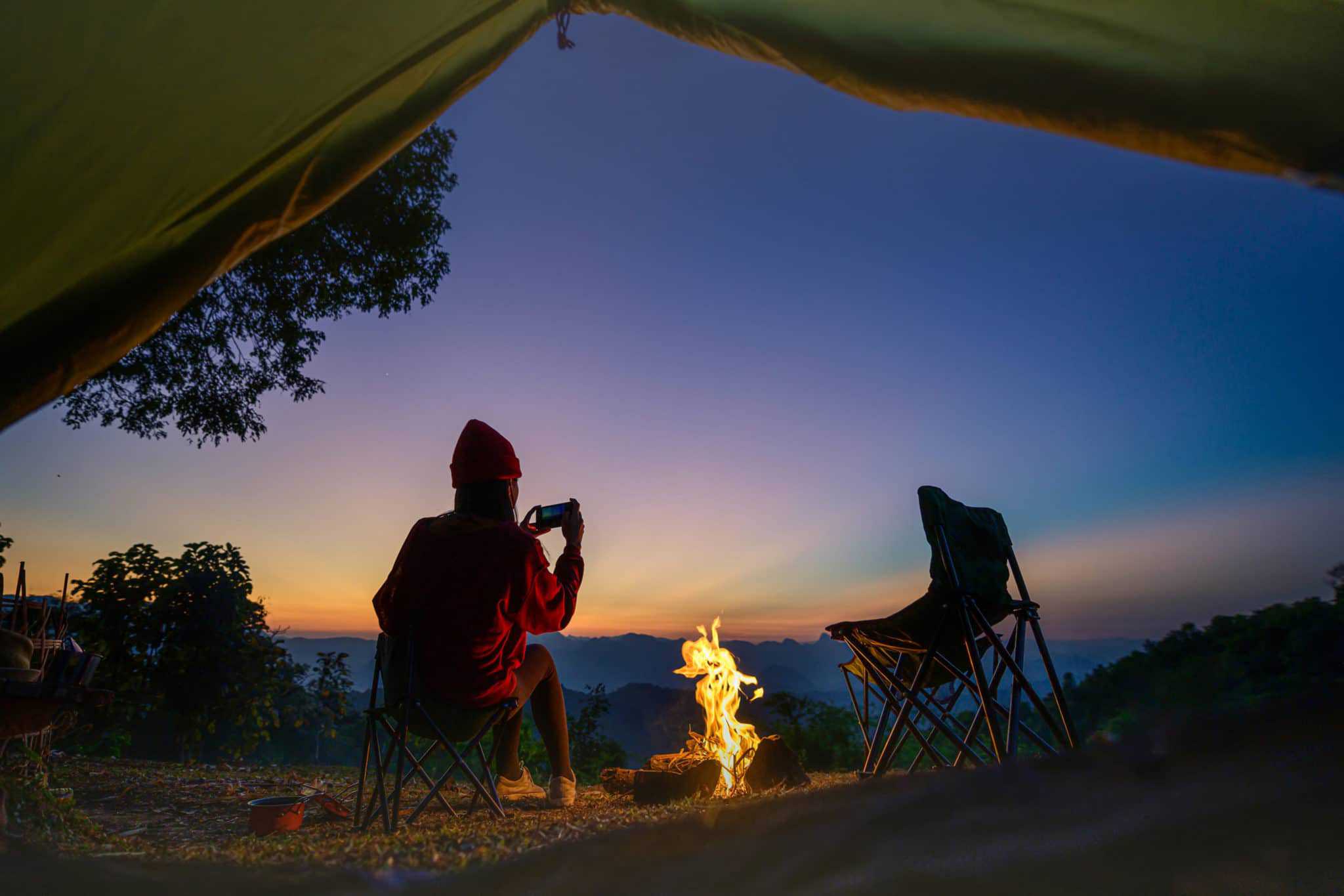 A person sits in a tent at sunset, enjoying the growing beauty of nature.