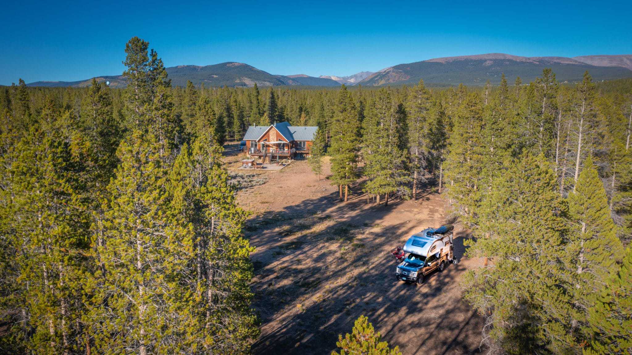 An aerial view of a cabin in the forest within a private RV camping network.