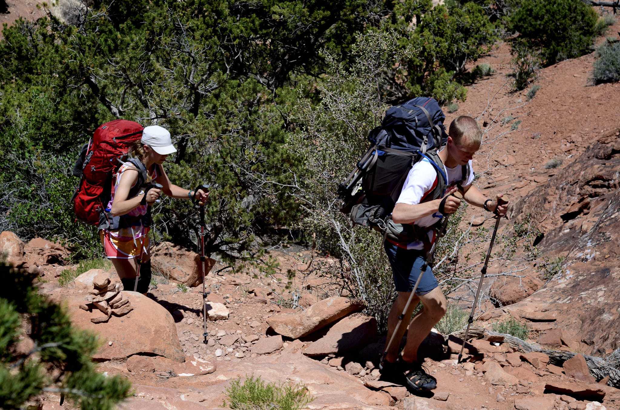 A man and a woman hiking up a rocky trail in Fiery Furnace.