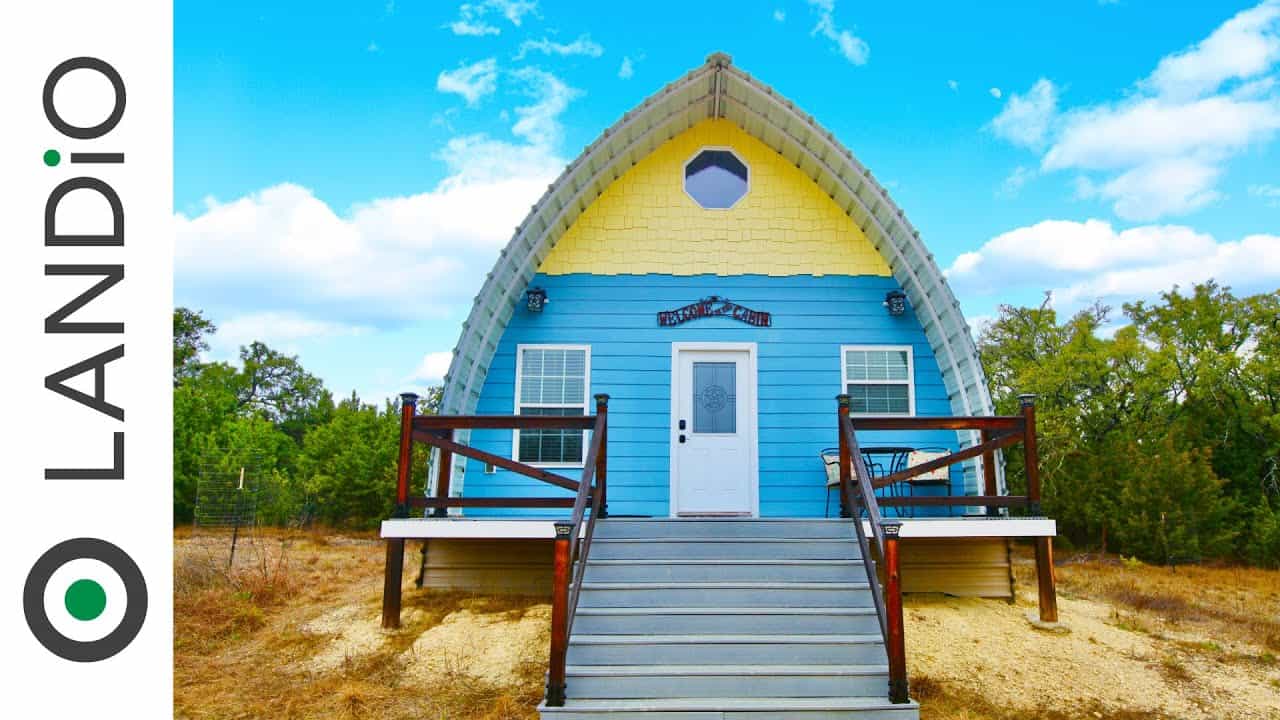 An arched blue and yellow house in the middle of a field.