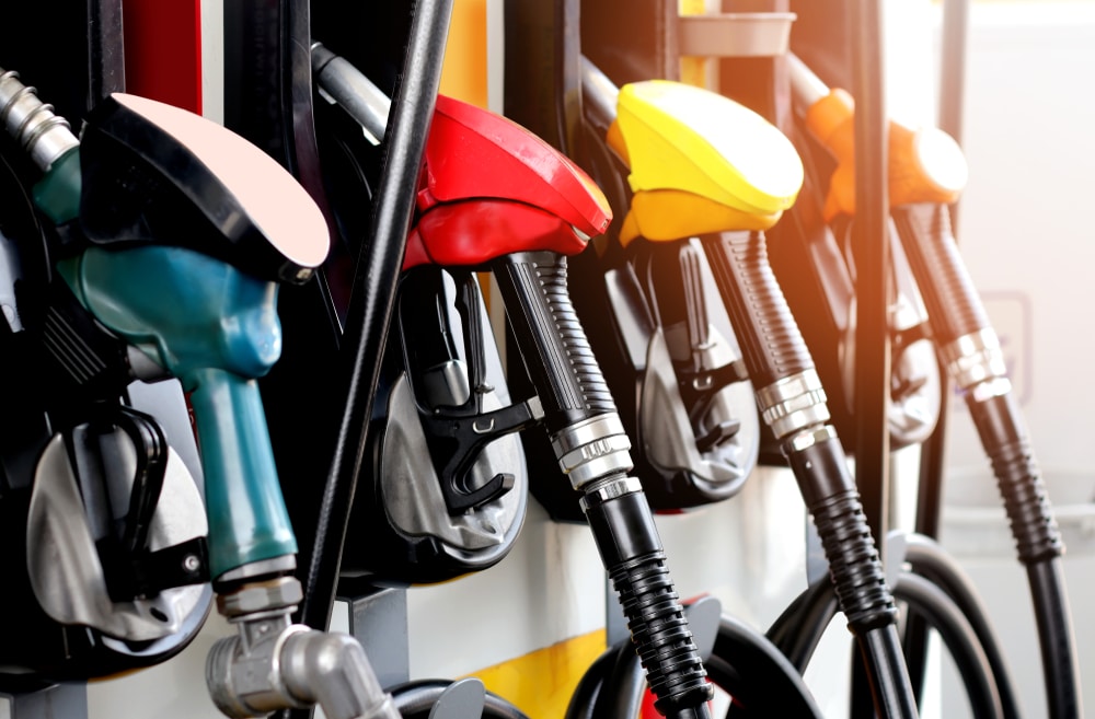 Gasoline pumps at a gas station with different colored nozzles, as the cost of fuel is steadily going up.