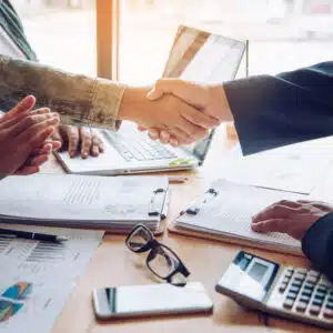 Two business people shaking hands at a desk during an ELS acquisition.