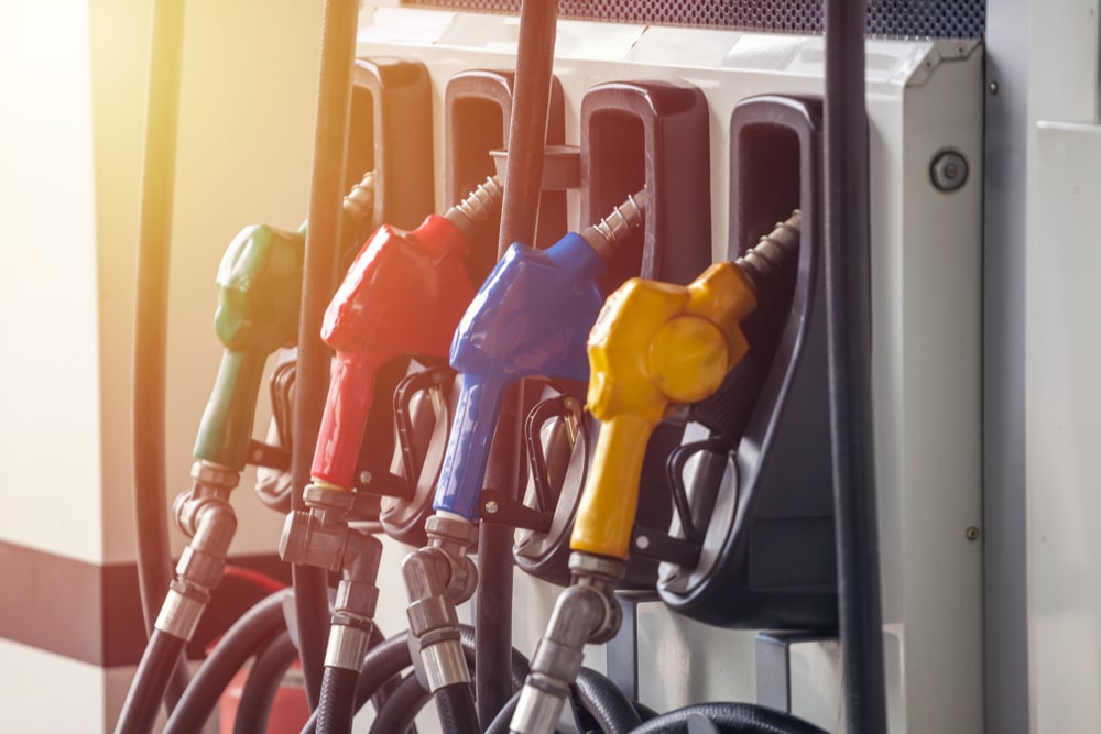A group of gas pumps with different colored nozzles, offering various pump prices.