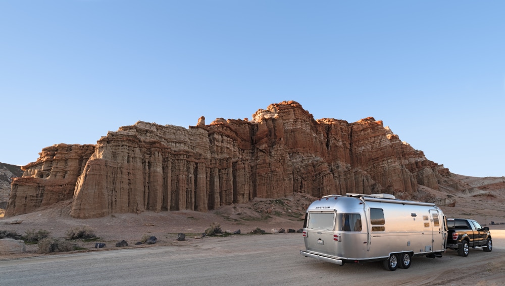 An RVDA-awarded silver Airstream parked on a dirt road.