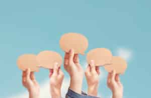 A group of hands holding paper speech bubbles discussing Land Management.