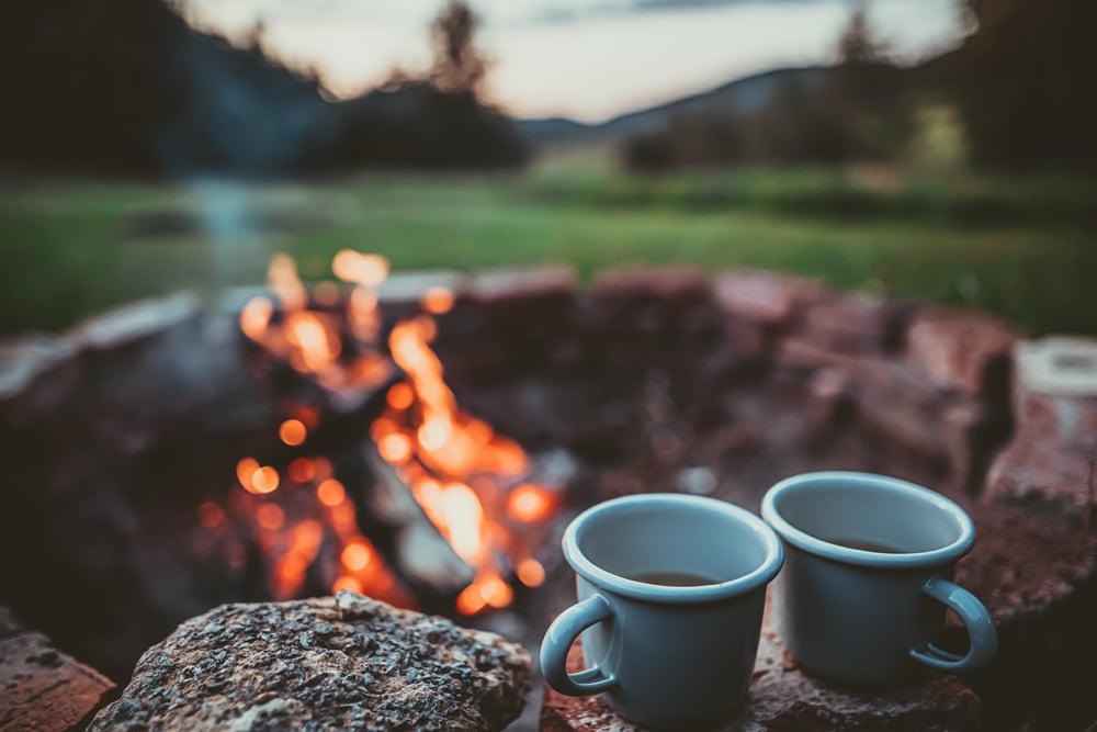 Two cups of coffee on a fire pit.