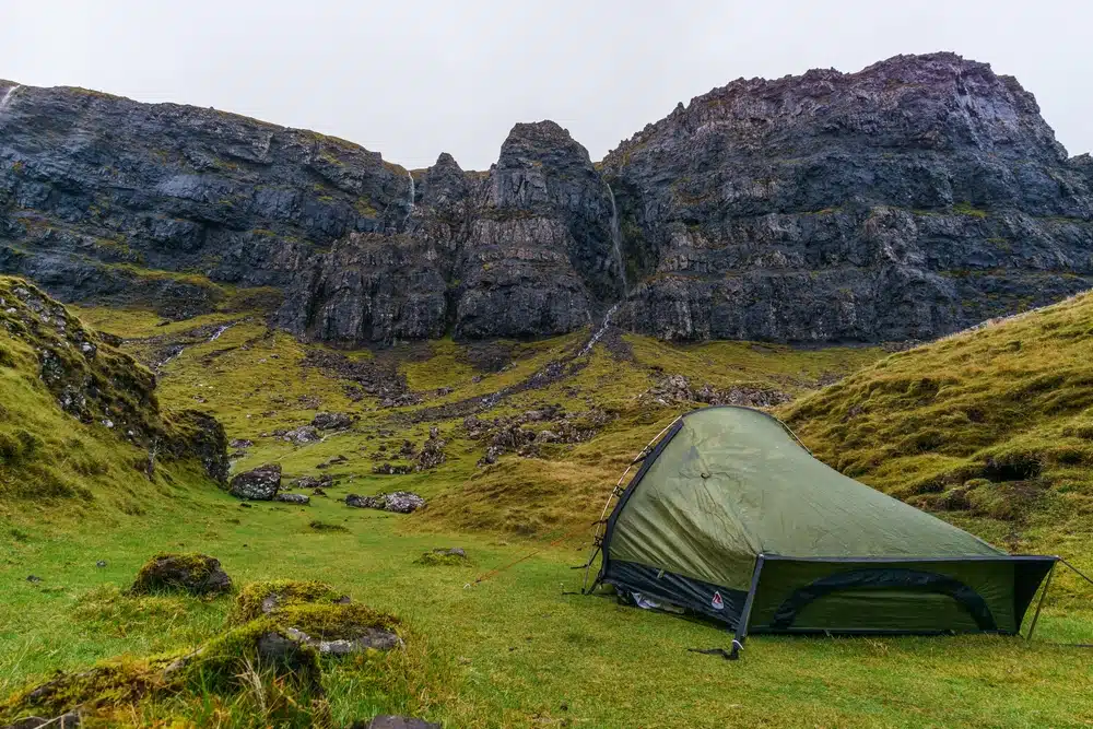 A new camping site in Scotland offering plans for setting up tents amidst a picturesque grassy area with stunning mountain views.