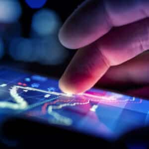 A hand is pointing at a graph displaying the drop in retail sales on a smartphone screen.