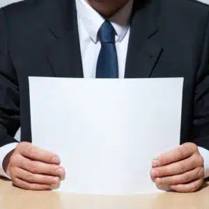 A man in a suit holding a proposed blank sheet of paper.
