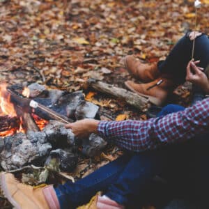 Two women sitting around a campfire in the woods.