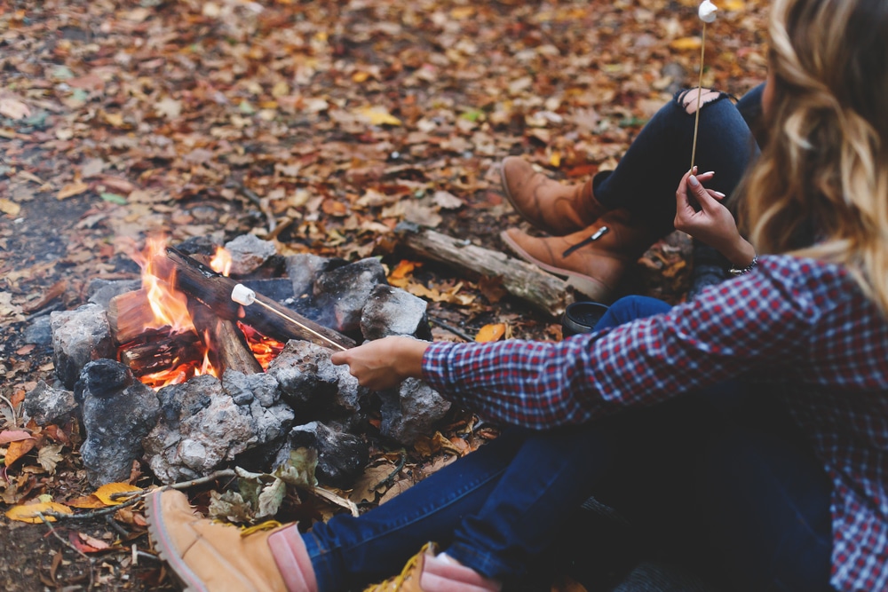 Two women sitting around a campfire in the woods.