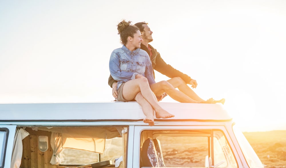 A couple enjoying a romantic sunset perch atop their van during the Third Quarter of the year.