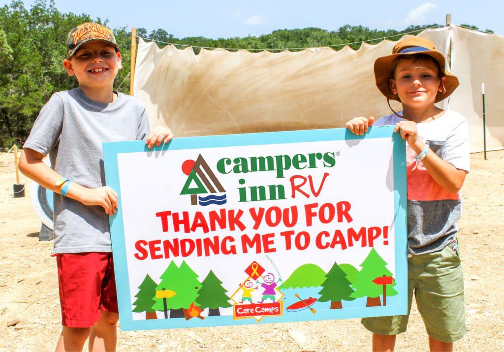 Two boys, thanks to Care Camps, proudly holding a sign that says thank you for sending me to camp.