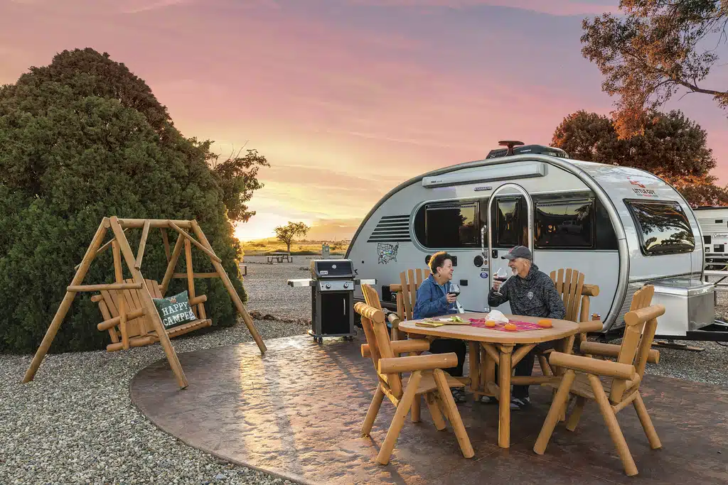 Two people sitting at a table in front of an airstream rv at the Willcox/Cochise KOA Holiday.
