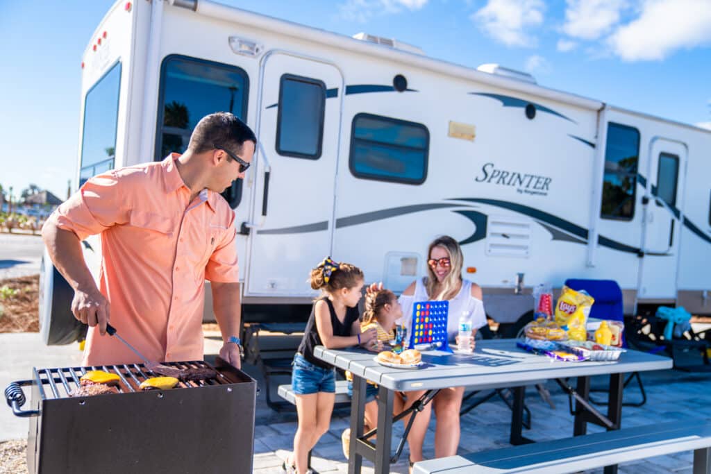 A man and woman grilling outside of an RV in a Florida RV Resort.