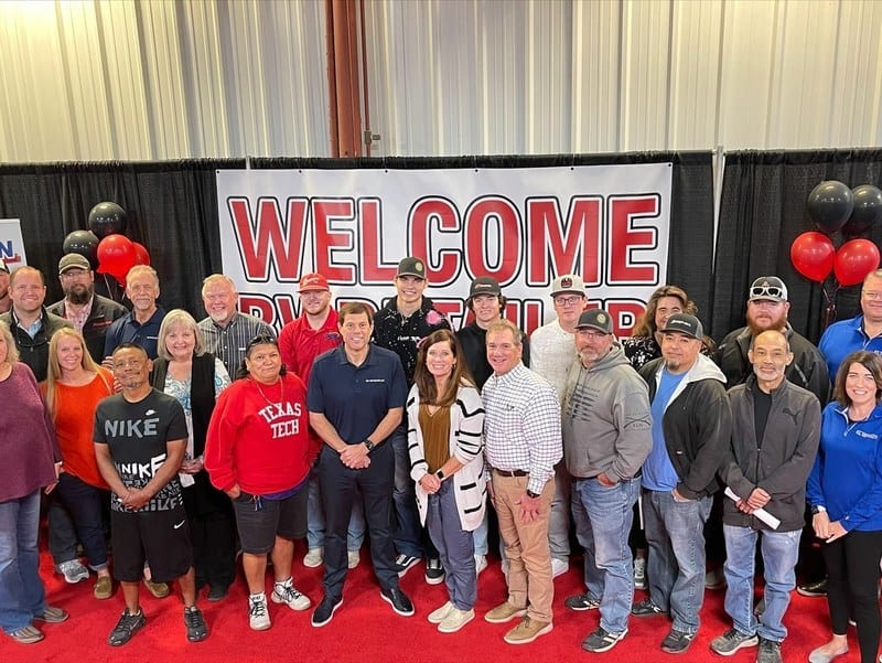 A group of people posing in front of an Affinity RV welcome sign.